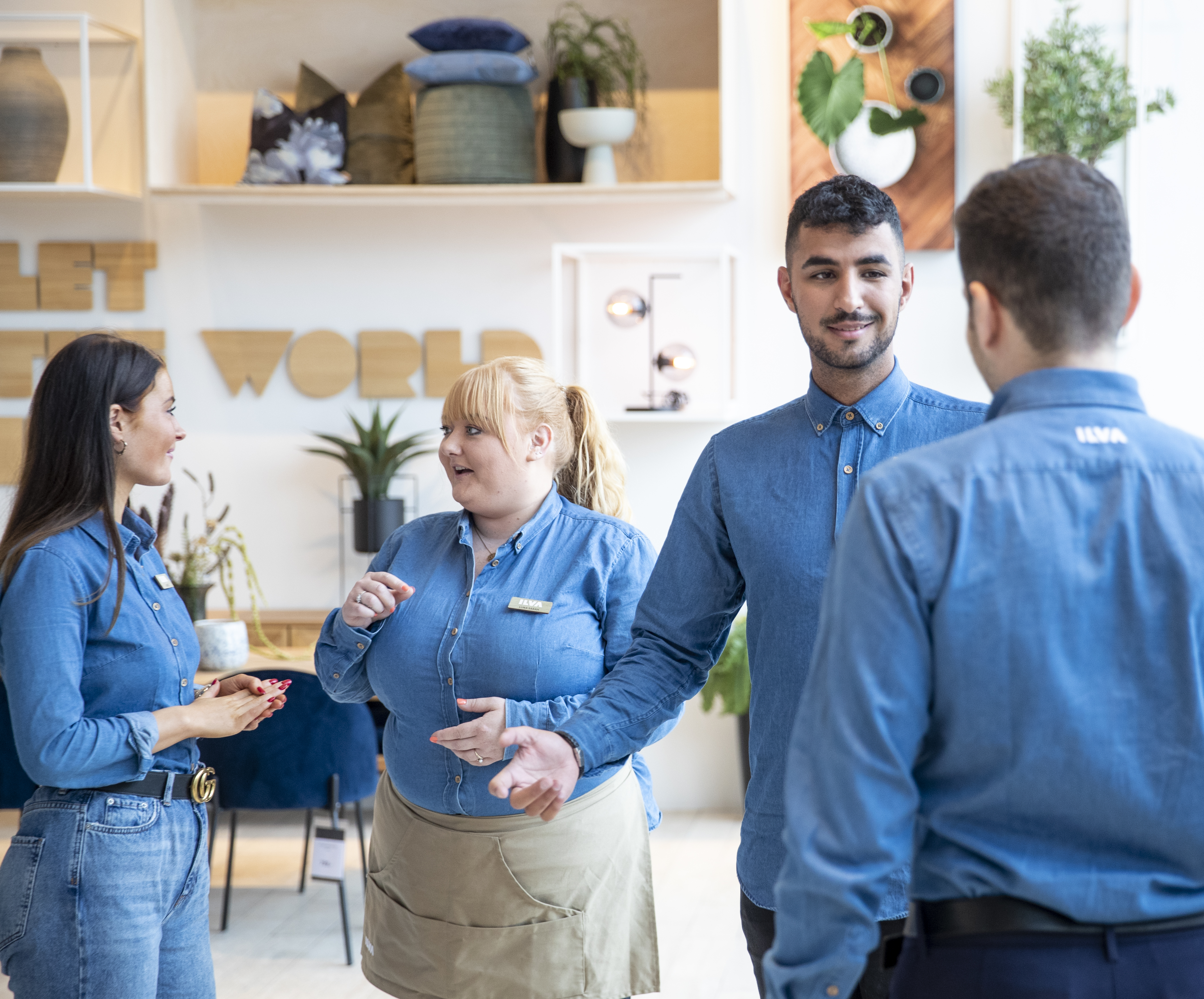 Medarbejdere i blå skjorter snakker i en moderne butik