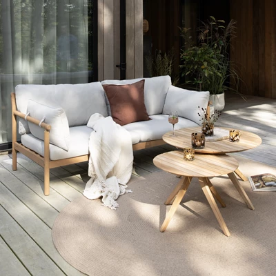 Udendørs sofa og borde på træterrasse med lanterner