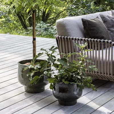 To sorte krukker foran fletsofa på terrasse.