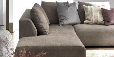 Design uden navn - 2024-12-27T230353.772.jpg Sofa med pufafslutning i gråt betræk. I sofaen er en masse puder i forskellige farver