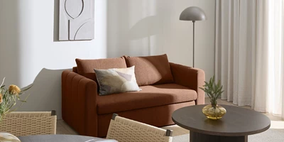 Moega.jpg Rød sovesofa i stue med gulvlampe og billede på væggen