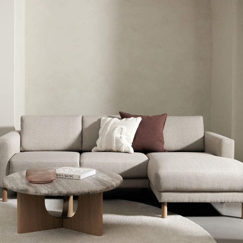 Sandfarvet chaiselongsofa i stue med sofabord med travertinbordplade