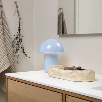 Lysblå bordlampe med kuppelform stående på badeværelse