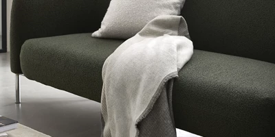 Lyst plaid liggende på grønlig sofa