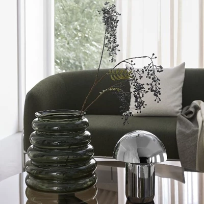 Rillet vase og krom bordlampe stående på glas sofabord