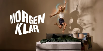 morgenklar-1535x768-glow.jpg Kvinde, der hopper i seng. Ved siden af er et stort logo med Morgenklar